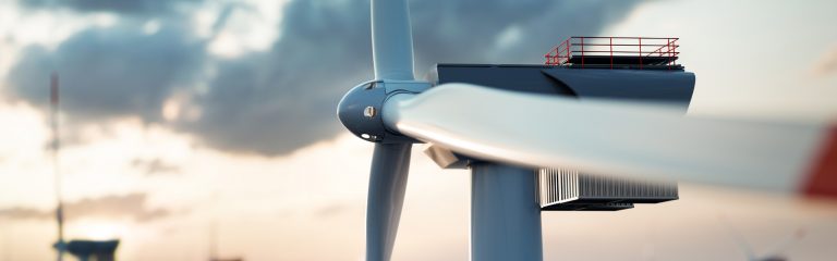 Close-up of a modern wind turbine with a cloudy sky in the background, showing the blades and nacelle in detail.